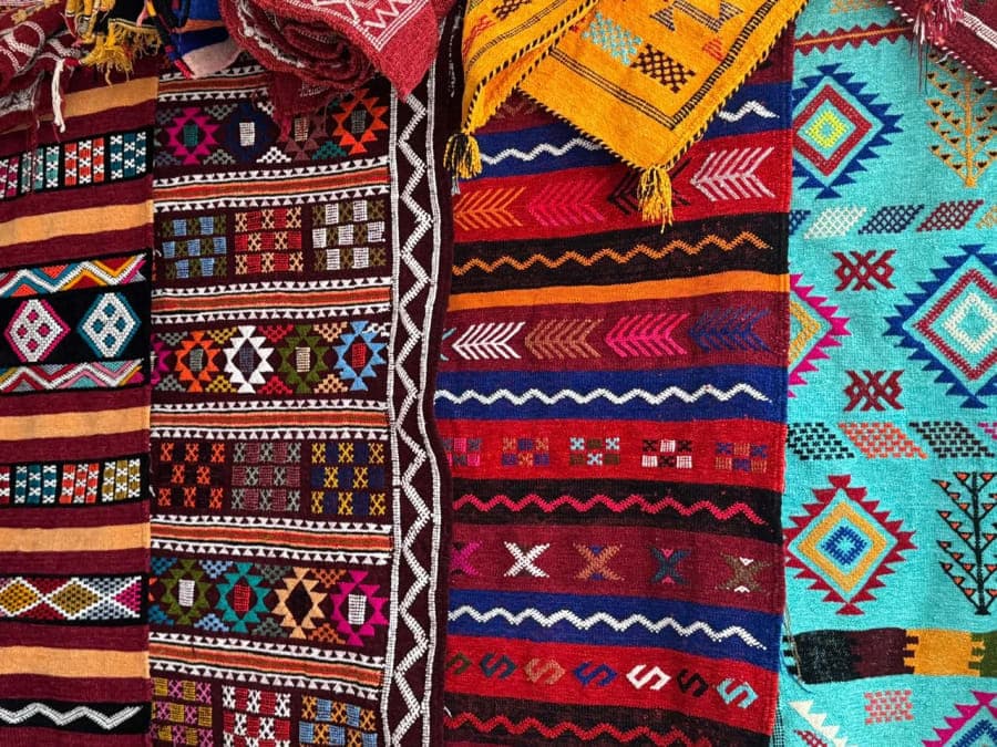 Plusieurs textiles colorés juxtaposent des motifs géométriques contrastés et des franges.